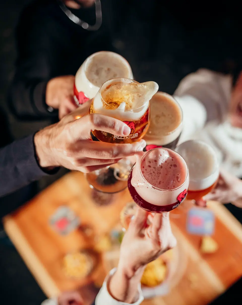 Um brinde com copos de cerveja e cocktails por cima de uma tábua de petiscos